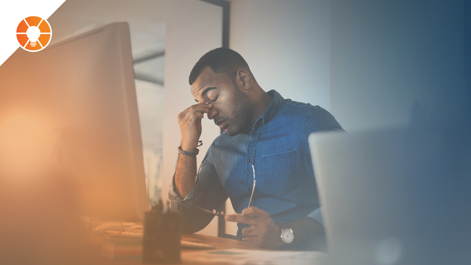 A person at a computer rubs the bridge of their nose in frustration